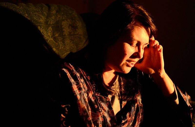 Image of woman with eyes closed and hand to head